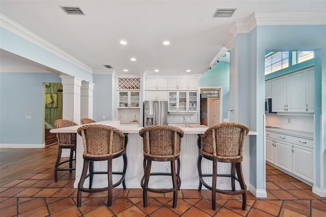 kitchen featuring crown molding, light countertops, visible vents, stainless steel fridge, and ornate columns