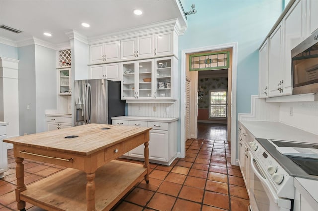 kitchen featuring visible vents, white cabinets, wooden counters, appliances with stainless steel finishes, and glass insert cabinets