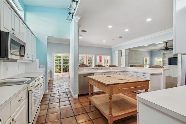 kitchen with appliances with stainless steel finishes, recessed lighting, ornamental molding, and a peninsula