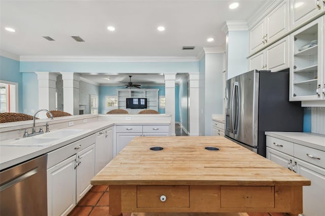 kitchen featuring decorative columns, wooden counters, appliances with stainless steel finishes, white cabinetry, and a sink