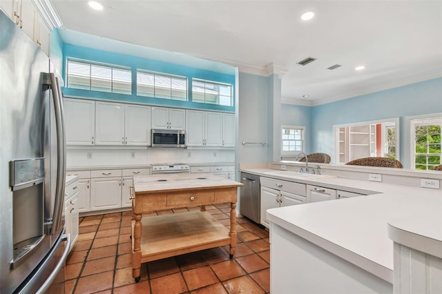 kitchen with stainless steel appliances, a sink, visible vents, light countertops, and crown molding