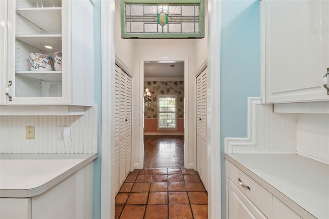 hall with baseboards and tile patterned floors