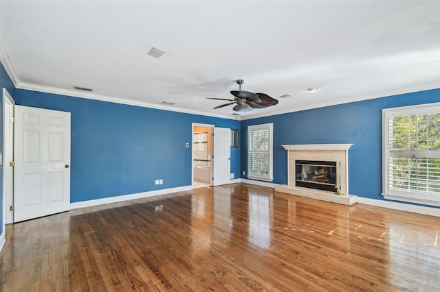 unfurnished living room featuring a glass covered fireplace, a healthy amount of sunlight, crown molding, and baseboards