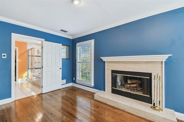 unfurnished living room with baseboards, visible vents, wood finished floors, crown molding, and a fireplace