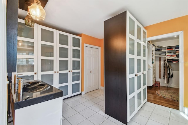 kitchen with light tile patterned flooring, a sink, glass insert cabinets, and white cabinetry