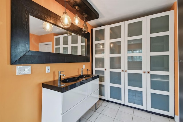 kitchen with pendant lighting, light tile patterned floors, dark countertops, glass insert cabinets, and white cabinets