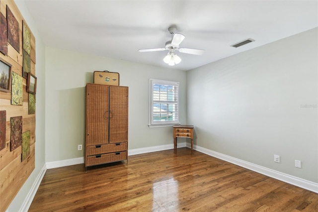 unfurnished room with visible vents, ceiling fan, baseboards, and wood finished floors