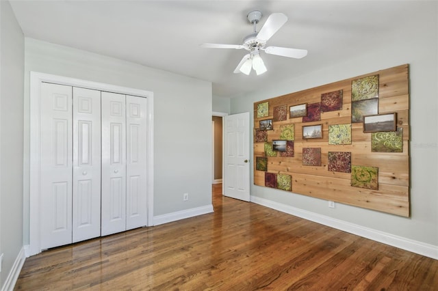 bedroom with a closet, wood finished floors, a ceiling fan, and baseboards