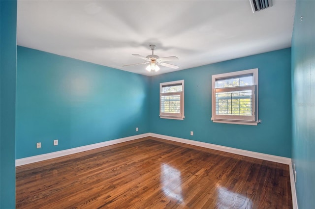 unfurnished room with baseboards, visible vents, ceiling fan, and dark wood-type flooring