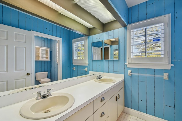 full bathroom with double vanity, a sink, and toilet