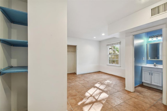 unfurnished room featuring light tile patterned flooring, a sink, visible vents, and recessed lighting