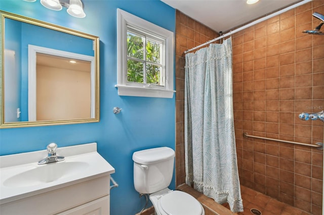 bathroom featuring toilet, a tile shower, and vanity