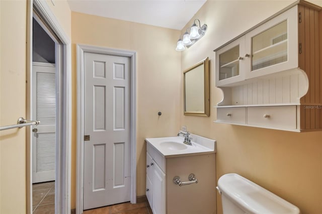 half bathroom featuring tile patterned flooring, vanity, and toilet