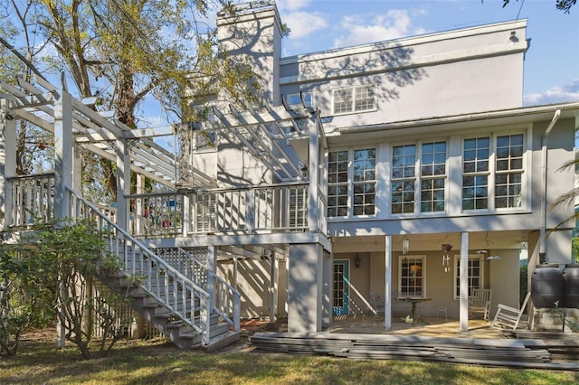 rear view of property with a deck, stairway, and stucco siding