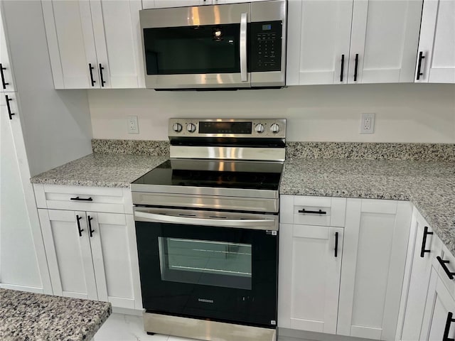 kitchen featuring light stone counters, stainless steel appliances, and white cabinets