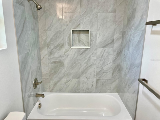 bathroom with toilet and tiled shower / bath