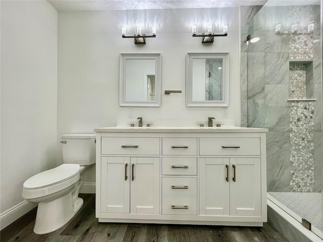 bathroom featuring hardwood / wood-style flooring, tiled shower, vanity, and toilet