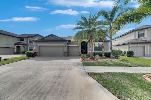 view of front of property with a front yard, a garage, driveway, and stucco siding