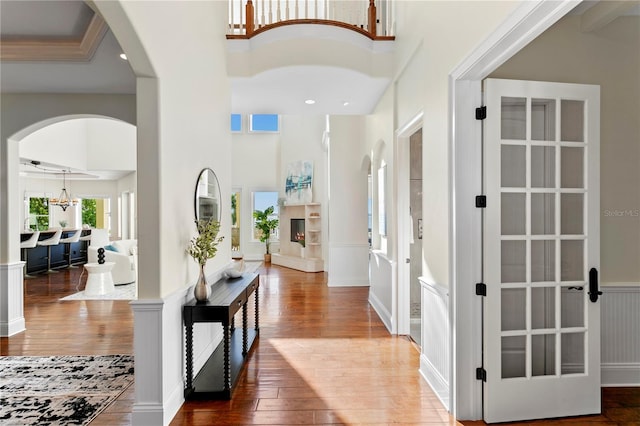 entrance foyer featuring hardwood / wood-style floors, recessed lighting, arched walkways, and a towering ceiling