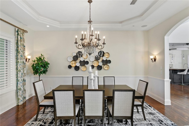 dining space with a raised ceiling, hardwood / wood-style flooring, and arched walkways