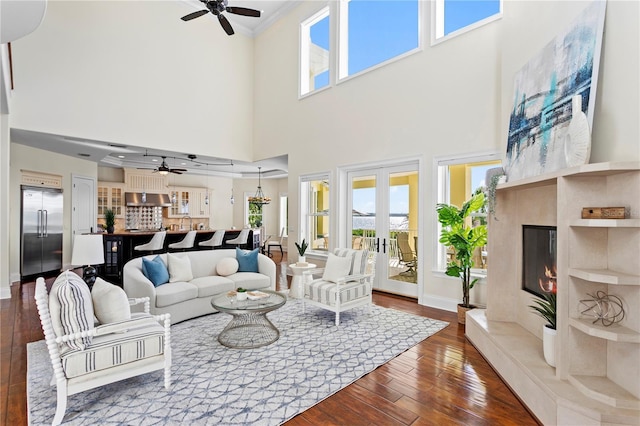 living area with a wealth of natural light, ceiling fan, and dark wood-style flooring