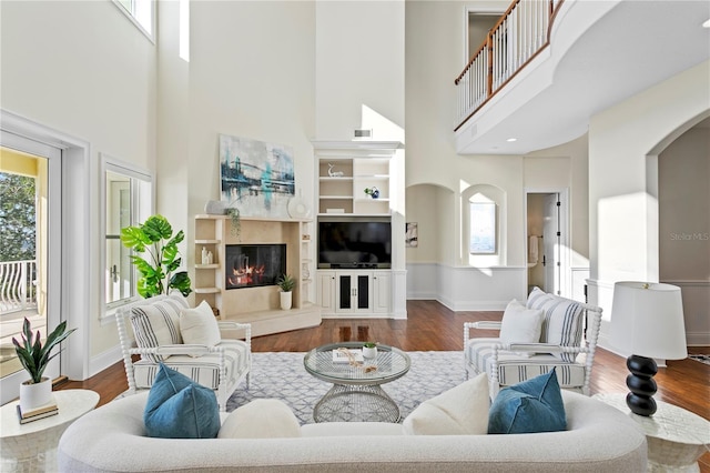 living area featuring arched walkways, visible vents, a fireplace, and wood finished floors