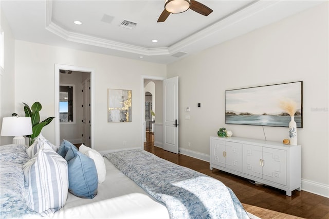 bedroom with arched walkways, visible vents, a raised ceiling, and dark wood-style floors