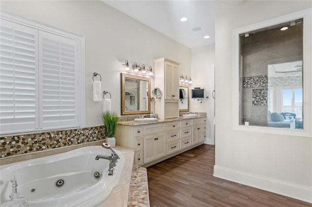 bathroom featuring a sink, wood finished floors, double vanity, baseboards, and a whirlpool tub