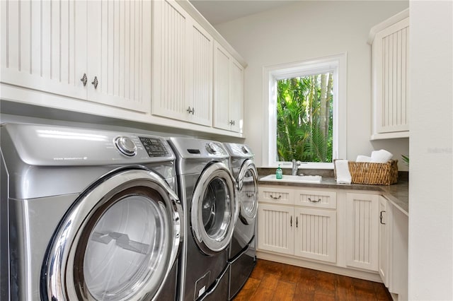 laundry area featuring cabinet space, separate washer and dryer, dark wood finished floors, and a sink