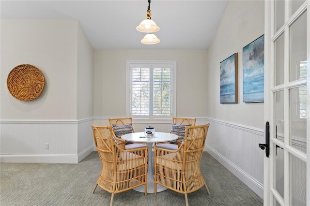 dining room with a wainscoted wall, carpet, and vaulted ceiling