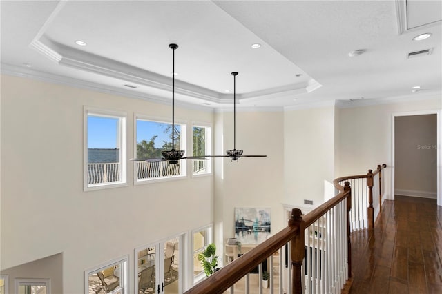 corridor featuring an upstairs landing, crown molding, a raised ceiling, and dark wood-type flooring