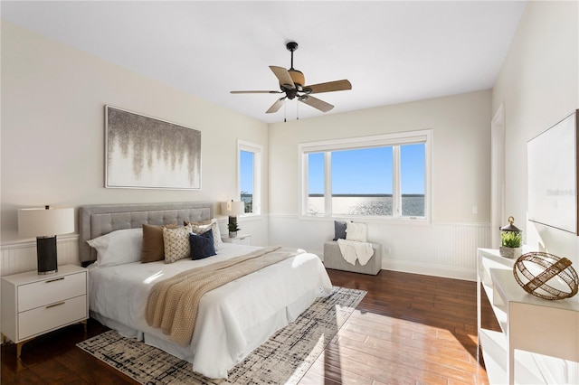 bedroom with hardwood / wood-style floors, ceiling fan, and wainscoting