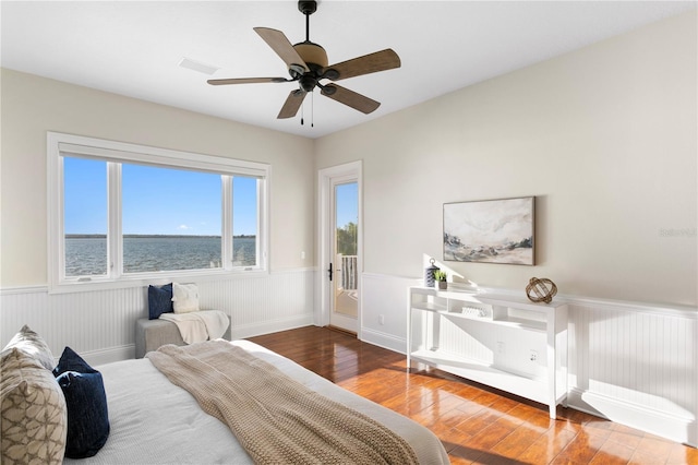 bedroom with visible vents, wainscoting, ceiling fan, and hardwood / wood-style floors