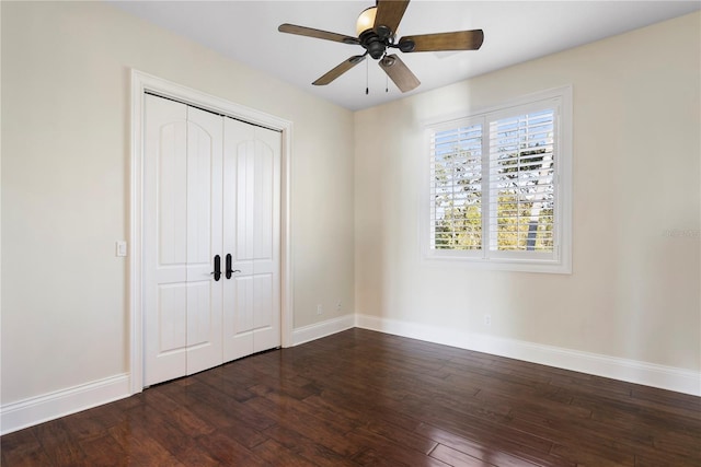 unfurnished bedroom featuring a closet, baseboards, ceiling fan, and dark wood-style flooring