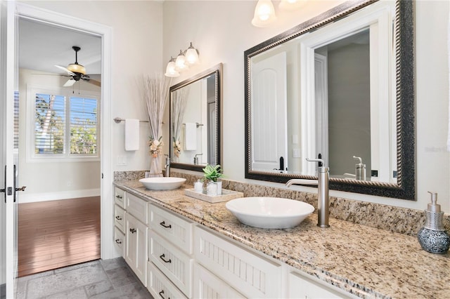 bathroom featuring double vanity, baseboards, a ceiling fan, and a sink