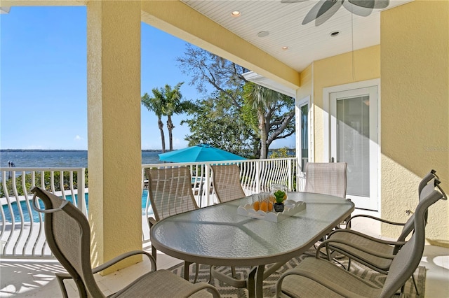 view of patio / terrace featuring outdoor dining space, a ceiling fan, an outdoor pool, and a water view