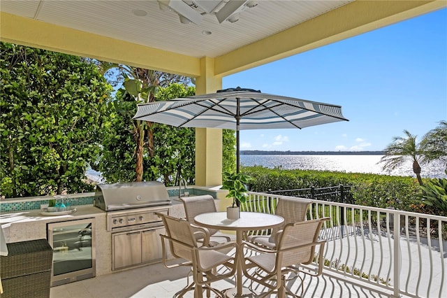 view of patio with outdoor dining space, exterior kitchen, a water view, and grilling area