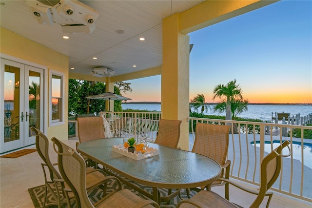 view of patio / terrace featuring a water view, french doors, an outdoor pool, outdoor dining area, and ceiling fan