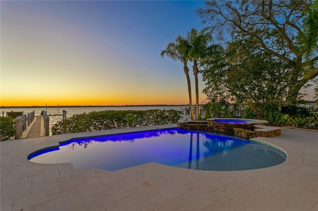 view of swimming pool featuring a water view, a patio, and a pool with connected hot tub