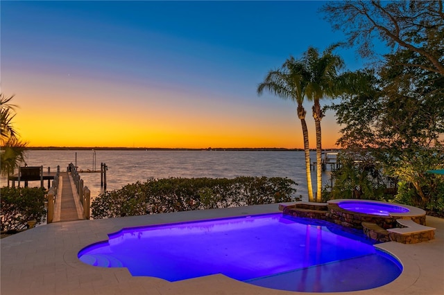 view of pool with a water view, a dock, and a pool with connected hot tub