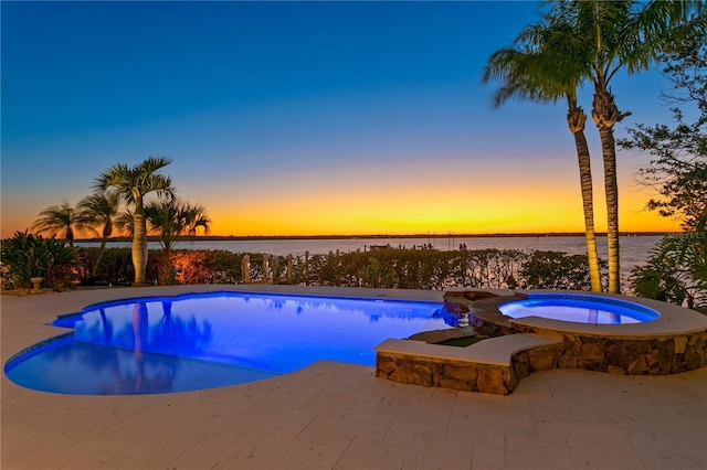 pool with an in ground hot tub, a patio, and a water view