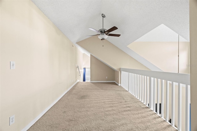 hall with lofted ceiling, light colored carpet, and a textured ceiling