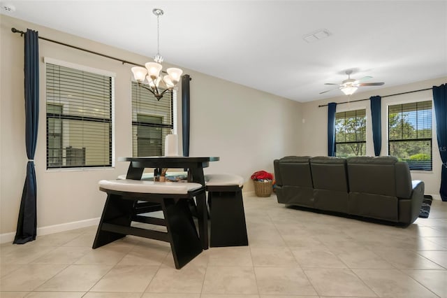 tiled dining room with ceiling fan with notable chandelier