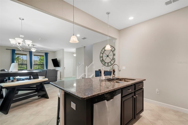 kitchen with pendant lighting, sink, dishwasher, an island with sink, and dark stone counters