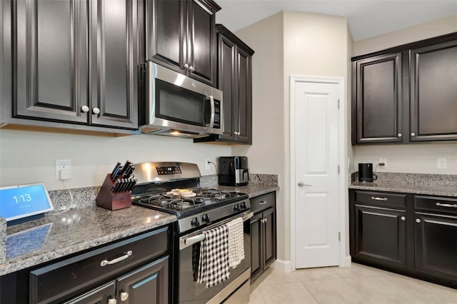 kitchen with stainless steel appliances, light stone countertops, and light tile patterned floors