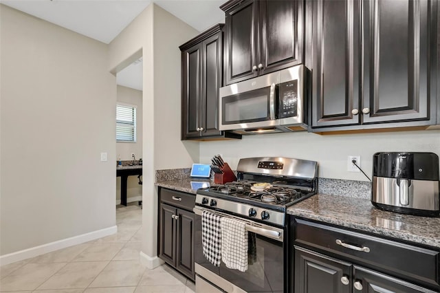 kitchen featuring dark stone countertops, light tile patterned floors, and stainless steel appliances