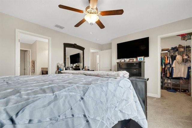 bedroom with a walk in closet, light colored carpet, a closet, and ceiling fan