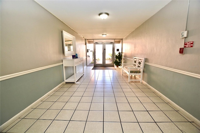 interior space featuring french doors, light tile patterned flooring, and baseboards