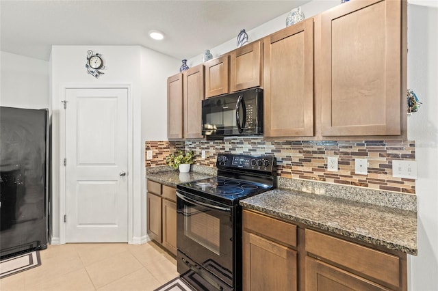 kitchen with tasteful backsplash, dark stone countertops, light tile patterned floors, and black appliances