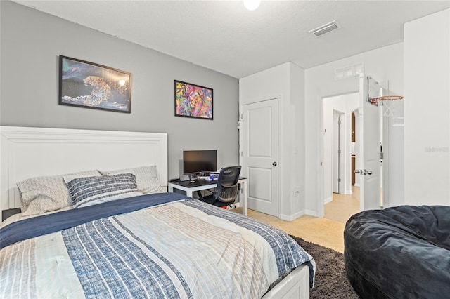 bedroom with light carpet and a textured ceiling